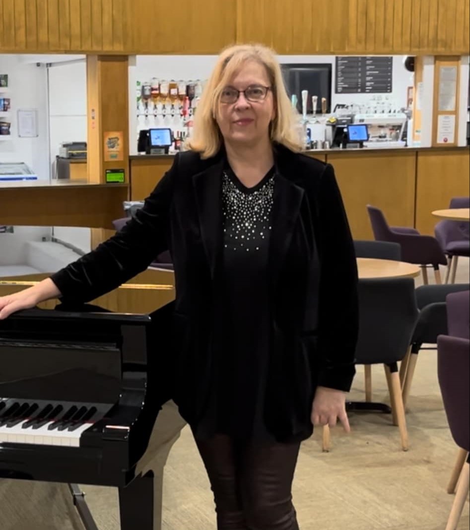 Caroline standing by a piano.